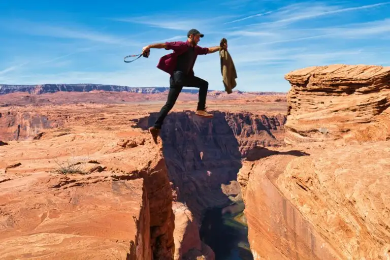 Man jumping over a canyon, showcasing adventure amidst breathtaking red rock landscape.