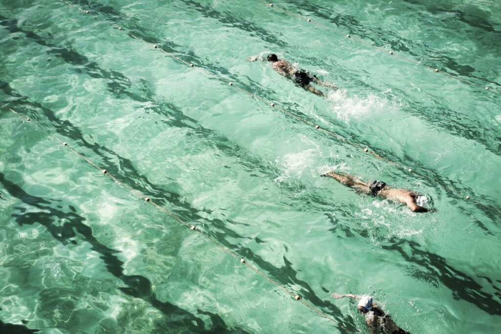 Swimmers in their lanes. One is ahead of another, showing that we need to be in the right lane, or right communication channel, for our message to be heard. 