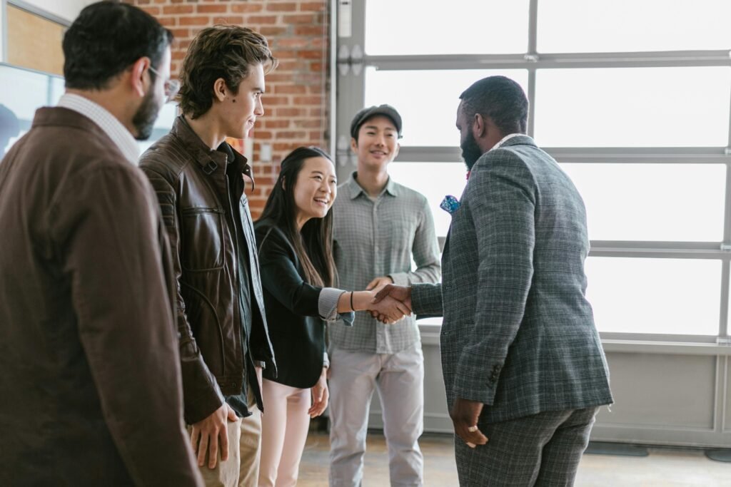 A diverse group of business professionals engaging in a handshake and pitc in a modern office space.